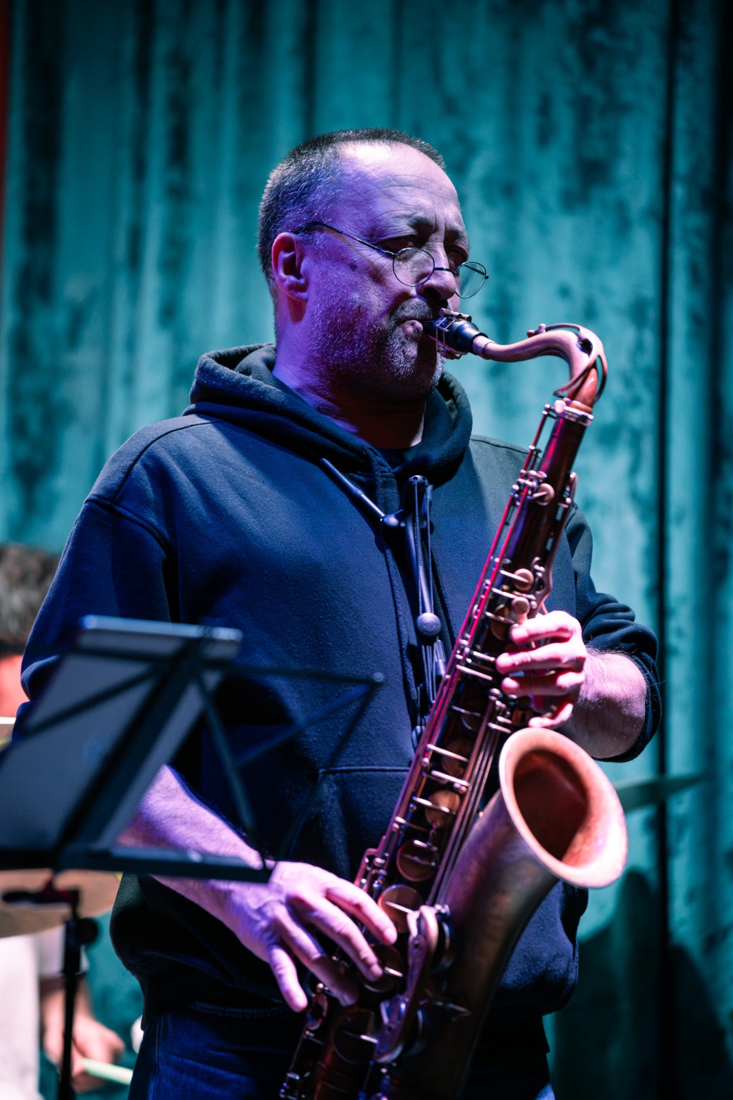 Saxophone player under stage light, raw and graded